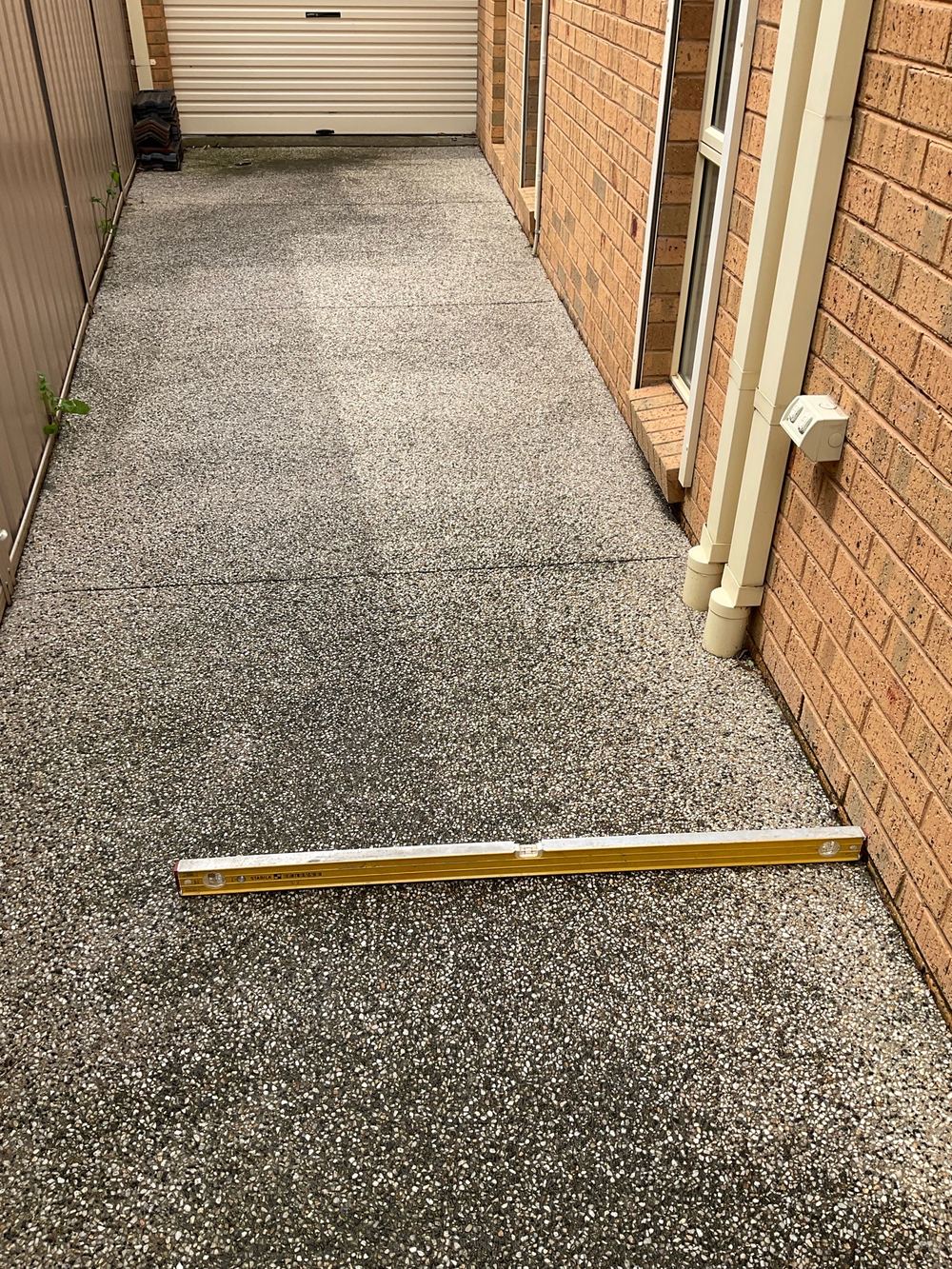 Spirit level showing paving pitched in toward the wall, found during a building and pest inspection in Sunshine North